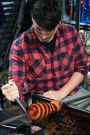 young man blowing glass during his gap year