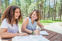 Two students outside at table studying