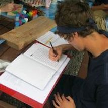 Teen writing in notebook at desk