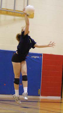 Teen hitting volleyball on court