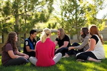Group of teens sitting in a circle on the grass