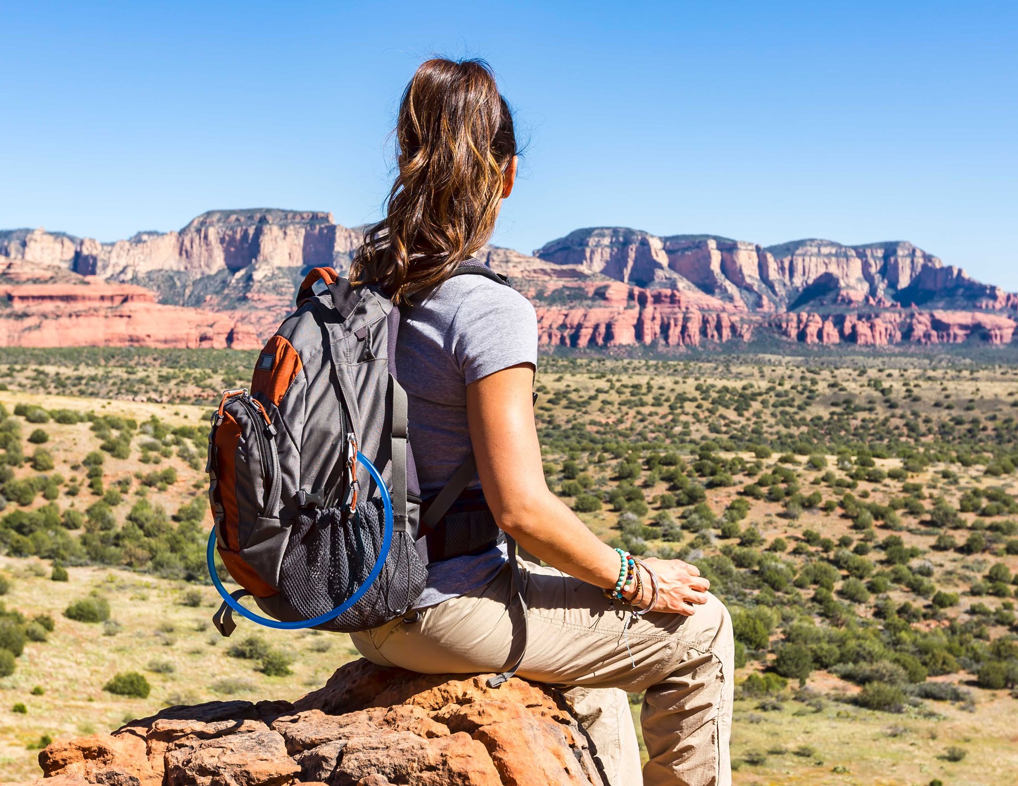 Photo of a young woman from the back with a backpack on looking out at Utah mountains.